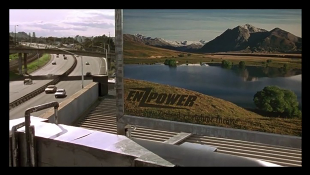 A billboard with a lake and mountains in the background  Description automatically generated