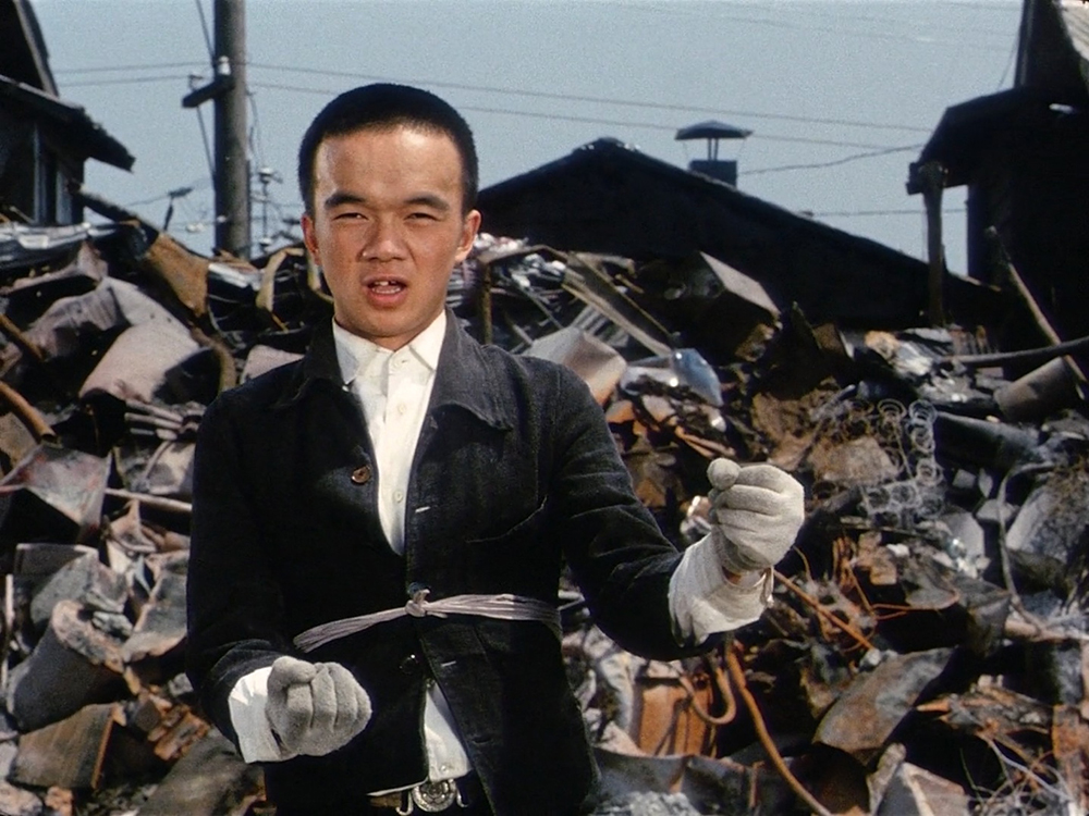 Rokuchan from Akira Kurosawa's Dodes'ka-den walking through a scrapyard while imagining himself driving a trolley through the slum.