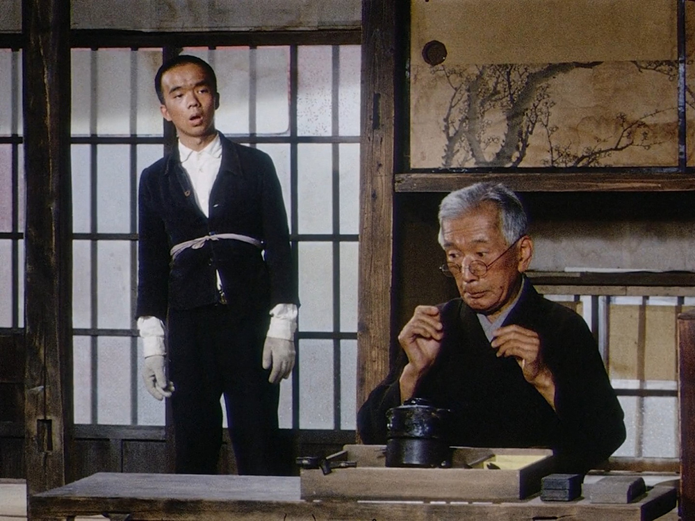 Rokuchan standing beside Mr. Tanba, the elderly silversmith and moral guide of the shantytown in Dodes'ka-den.
