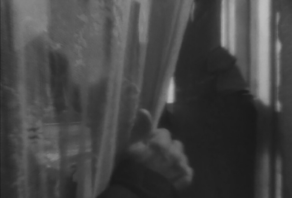 Blurred point-of-view shot of O closing window curtains, illustrating the dreamlike quality of O's vision.