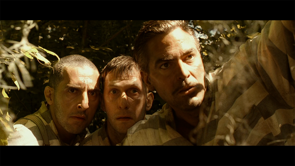 Three escaped convicts from O Brother, Where Art Thou? peering through foliage during their search for treasure and answers.