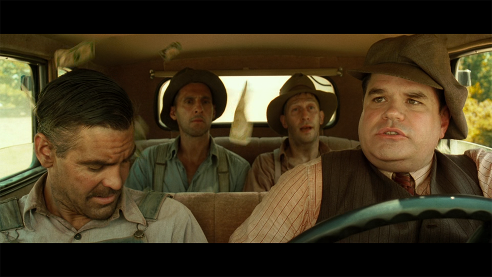 George Nelson driving with the escaped convicts in O Brother, Where Art Thou?, framed as desperadoes on the road.